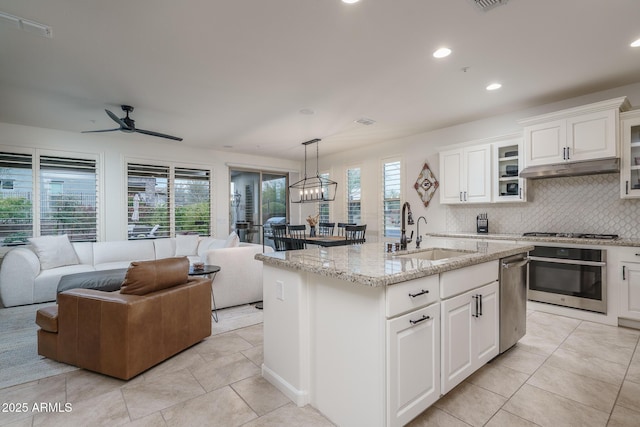 kitchen featuring sink, hanging light fixtures, a center island with sink, stainless steel appliances, and white cabinets