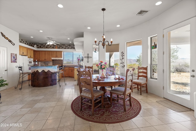 dining space with light tile patterned flooring and ceiling fan with notable chandelier