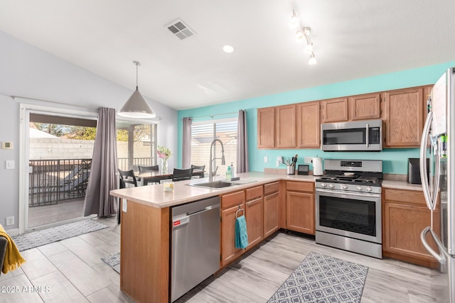 kitchen featuring lofted ceiling, sink, decorative light fixtures, kitchen peninsula, and stainless steel appliances