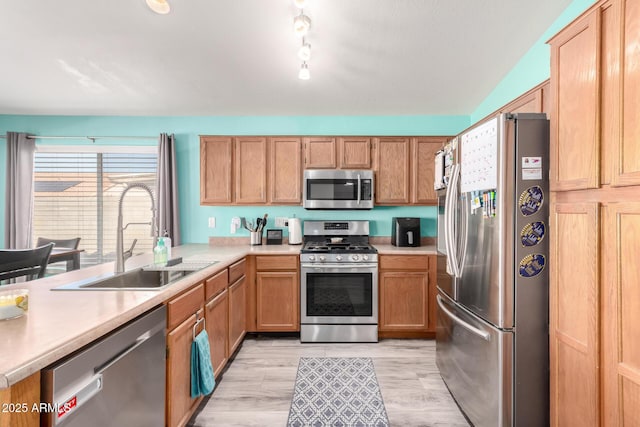 kitchen featuring appliances with stainless steel finishes, sink, and light hardwood / wood-style floors