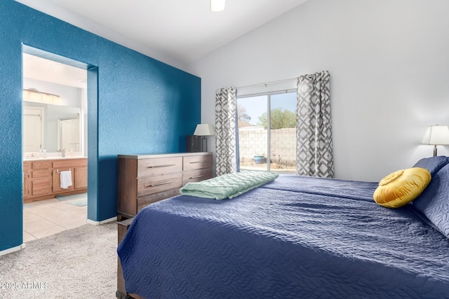 carpeted bedroom with ensuite bathroom, lofted ceiling, sink, and access to exterior