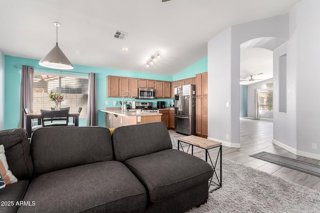 living room with vaulted ceiling, light hardwood / wood-style floors, ceiling fan, and plenty of natural light