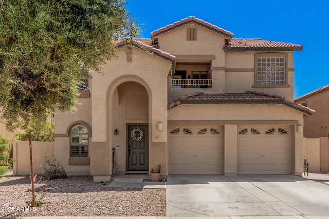 mediterranean / spanish-style home featuring a tile roof, driveway, a garage, a balcony, and stucco siding