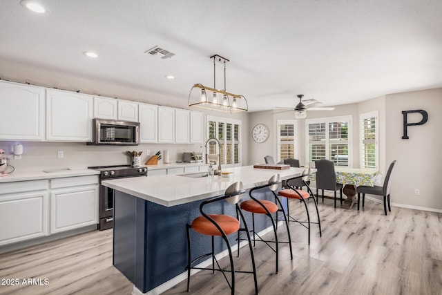 kitchen with white cabinets, a breakfast bar, visible vents, a sink, and appliances with stainless steel finishes