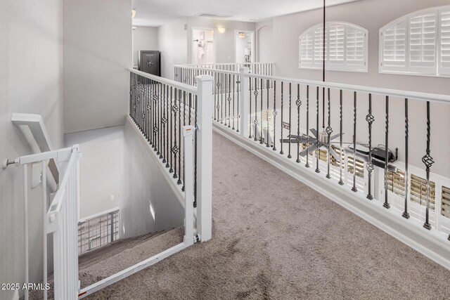 hall featuring carpet flooring and an upstairs landing