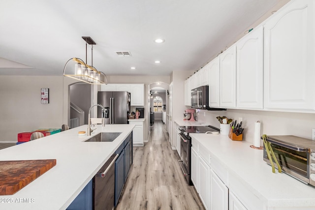 kitchen with arched walkways, a sink, high end refrigerator, visible vents, and black electric range