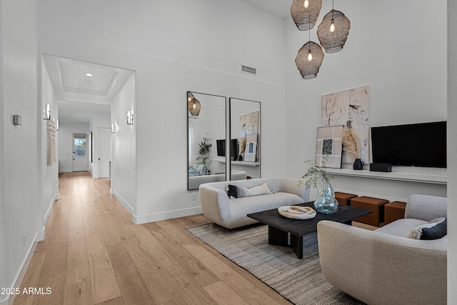 living room with a towering ceiling and light wood-type flooring