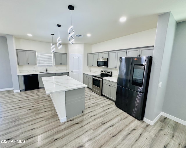 kitchen with recessed lighting, gray cabinets, a sink, baseboards, and appliances with stainless steel finishes