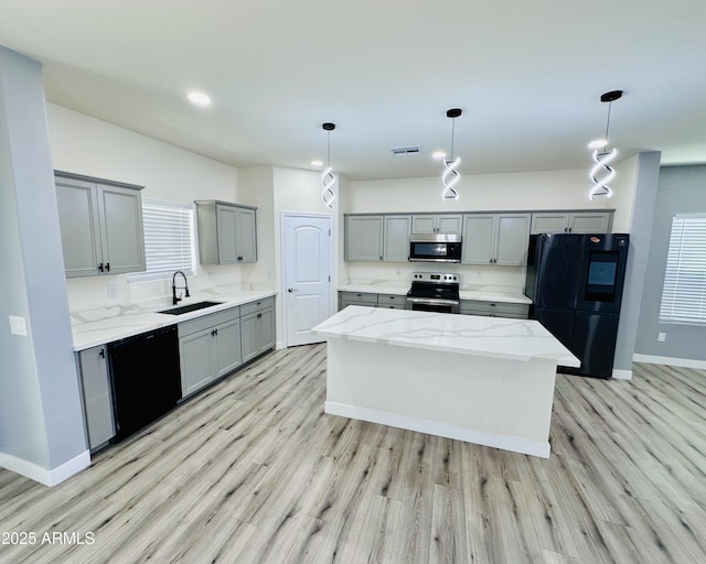 kitchen featuring gray cabinets, black appliances, a sink, and light wood-style flooring