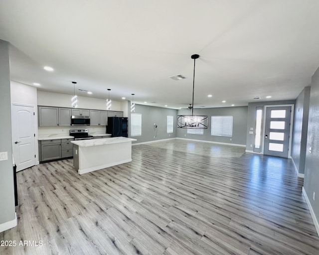 kitchen featuring recessed lighting, stainless steel appliances, gray cabinets, baseboards, and open floor plan