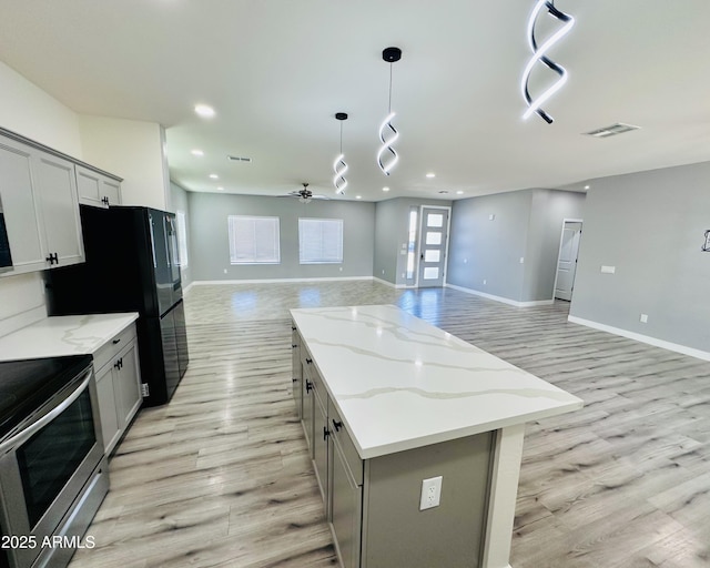 kitchen with light wood-style flooring, open floor plan, gray cabinetry, stainless steel range with electric stovetop, and ceiling fan