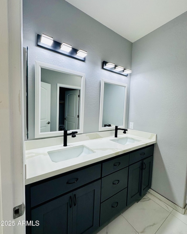full bathroom featuring double vanity, marble finish floor, and a sink