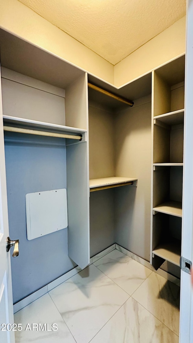 walk in closet featuring marble finish floor