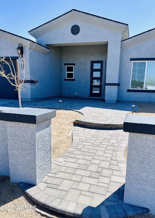 rear view of house with stucco siding and a patio area