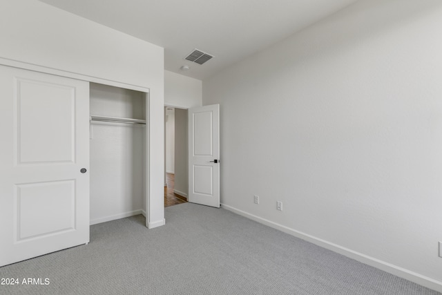 unfurnished bedroom with light carpet and a closet