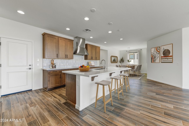 kitchen featuring a center island with sink, wall chimney exhaust hood, sink, and dark hardwood / wood-style flooring