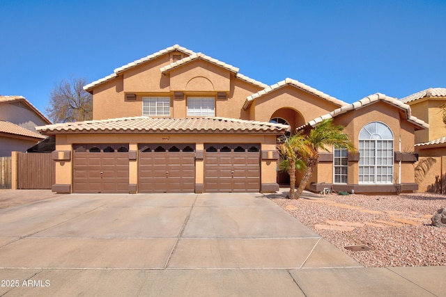 mediterranean / spanish-style house with a tiled roof, driveway, fence, and stucco siding