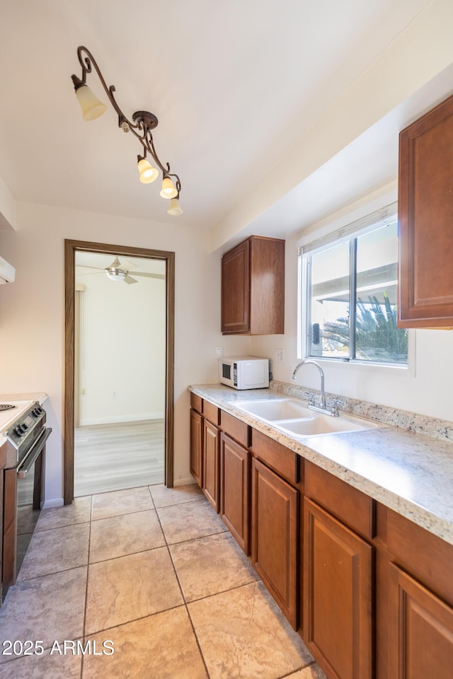 kitchen featuring sink, light tile patterned floors, and stainless steel range oven