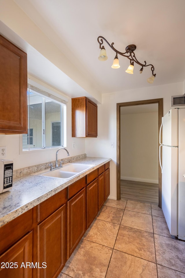 kitchen with light tile patterned flooring, sink, and white fridge