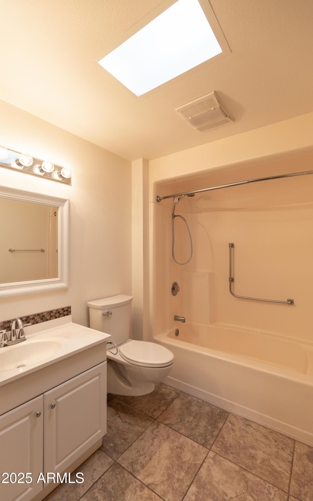 full bathroom featuring a skylight, vanity, bathtub / shower combination, and toilet