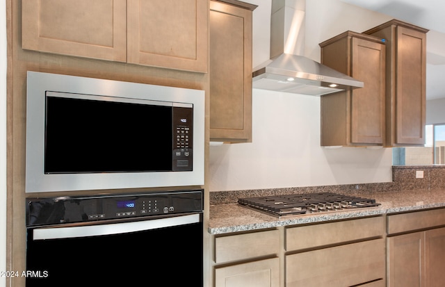 kitchen with stone countertops, stainless steel appliances, and wall chimney exhaust hood