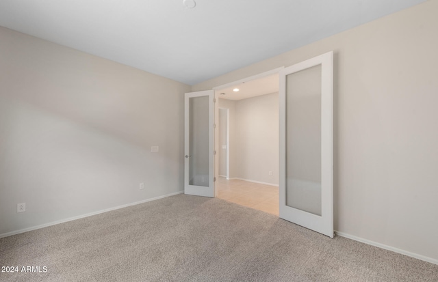 unfurnished bedroom with light colored carpet and french doors