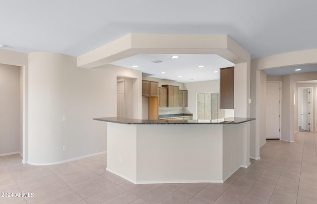 kitchen with light tile patterned floors and dark stone countertops