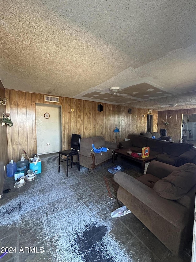 living room featuring a textured ceiling and wood walls