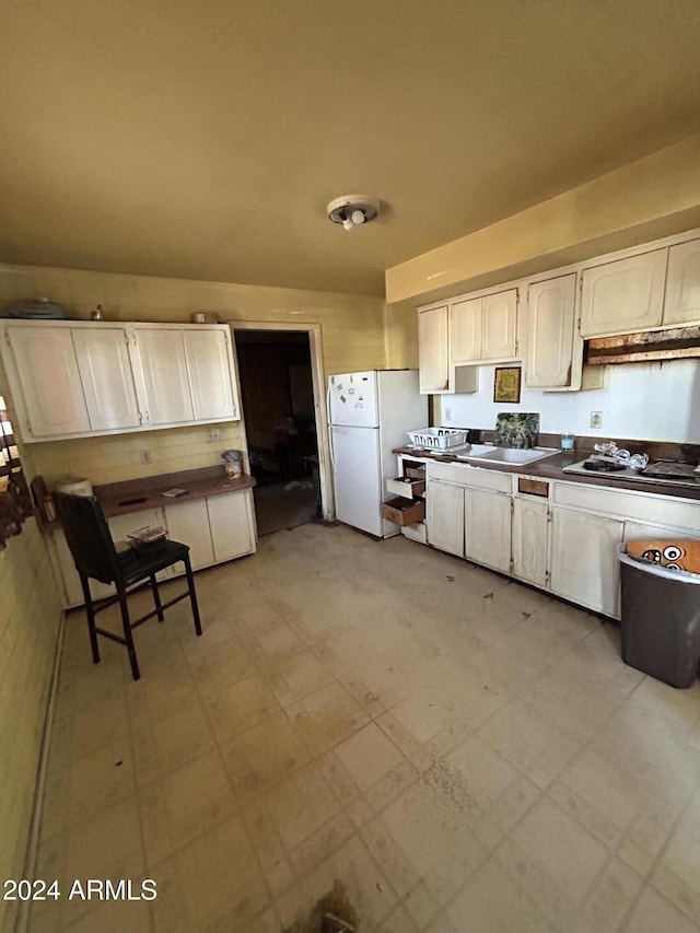 kitchen featuring white cabinets, sink, white fridge, and gas stovetop