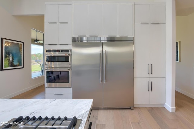 12225 E Cortez Dr, Scottsdale, AZ 85259 - kitchen featuring light wood finished floors, baseboards, white cabinetry, and appliances with stainless steel finishes