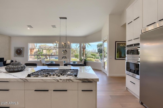 12225 E Cortez Dr, Scottsdale, AZ 85259 - kitchen with light stone countertops, white cabinetry, visible vents, stainless steel appliances, and light wood finished floors
