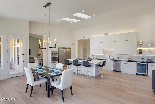 12225 E Cortez Dr, Scottsdale, AZ 85259 - dining room featuring a chandelier, a skylight, high vaulted ceiling, light wood finished floors, and beverage cooler