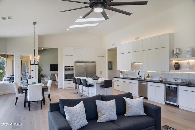 12225 E Cortez Dr, Scottsdale, AZ 85259 - living room featuring ceiling fan with notable chandelier, high vaulted ceiling, visible vents, wine cooler, and light wood finished floors