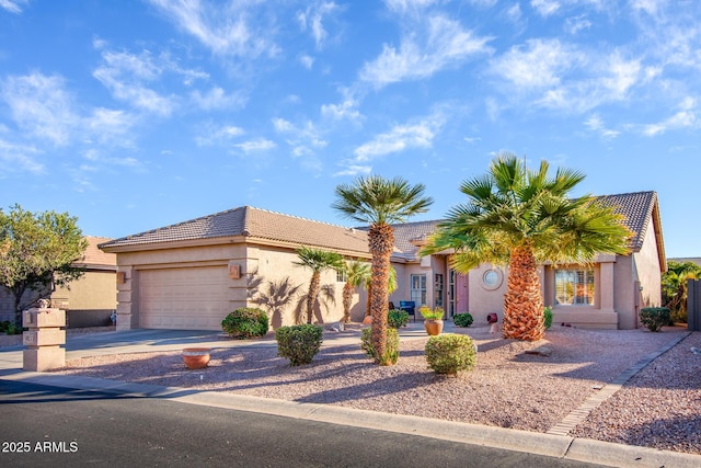 view of front facade featuring a garage, a tile roof, driveway, and stucco siding