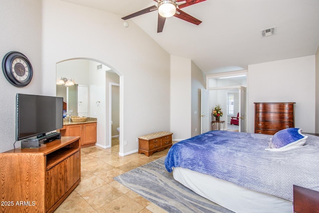 bedroom with lofted ceiling, light tile patterned floors, arched walkways, visible vents, and baseboards