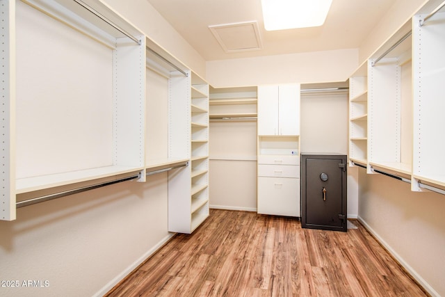 walk in closet with light wood finished floors and attic access