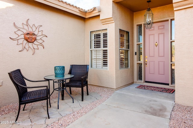 entrance to property with a tiled roof, a patio, and stucco siding