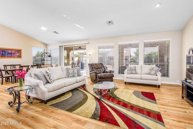 living area featuring lofted ceiling, recessed lighting, visible vents, wood finished floors, and baseboards