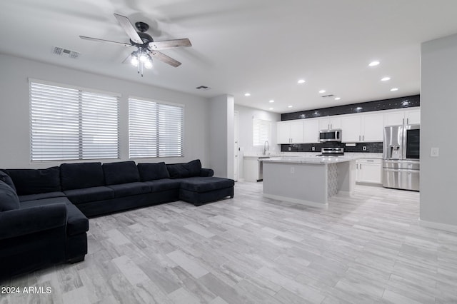 living room with light hardwood / wood-style flooring, ceiling fan, and sink