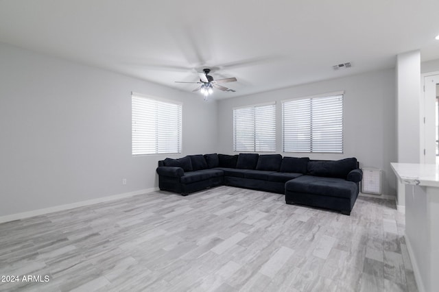 living room with light wood-type flooring, ceiling fan, and a healthy amount of sunlight