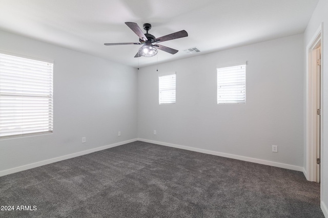 spare room with dark colored carpet and ceiling fan