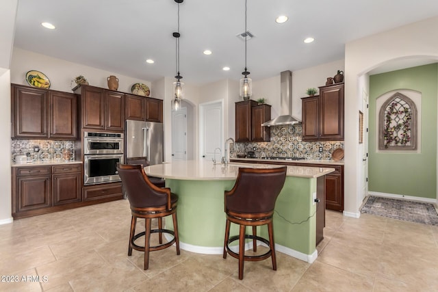 4149 N Brigadier Dr, Florence, AZ 85132 - kitchen with a center island with sink, appliances with stainless steel finishes, hanging light fixtures, light countertops, and wall chimney range hood