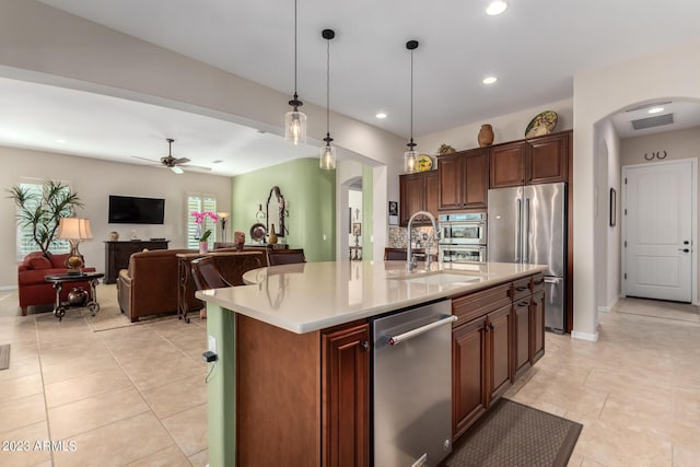 4149 N Brigadier Dr, Florence, AZ 85132 - kitchen featuring arched walkways, a center island with sink, stainless steel appliances, light countertops, and a sink