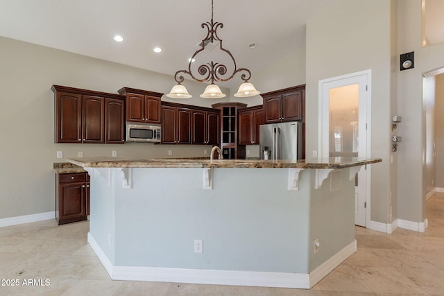 2701 E Caldwell St, Phoenix, AZ 85042 - kitchen featuring appliances with stainless steel finishes, a breakfast bar, a sink, light stone counters, and pendant lighting