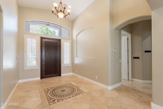 2701 E Caldwell St, Phoenix, AZ 85042 - foyer featuring an inviting chandelier, arched walkways, high vaulted ceiling, baseboards, and light tile patterned floors