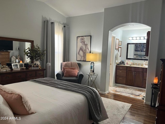 bedroom featuring connected bathroom, vaulted ceiling, dark hardwood / wood-style flooring, and sink