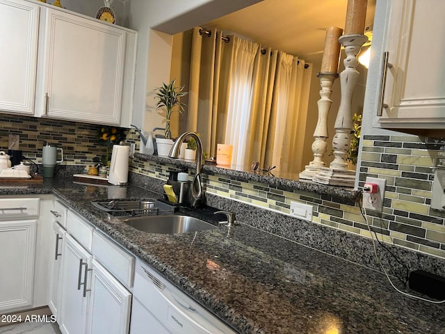 kitchen featuring tasteful backsplash, dark stone countertops, sink, and white cabinets