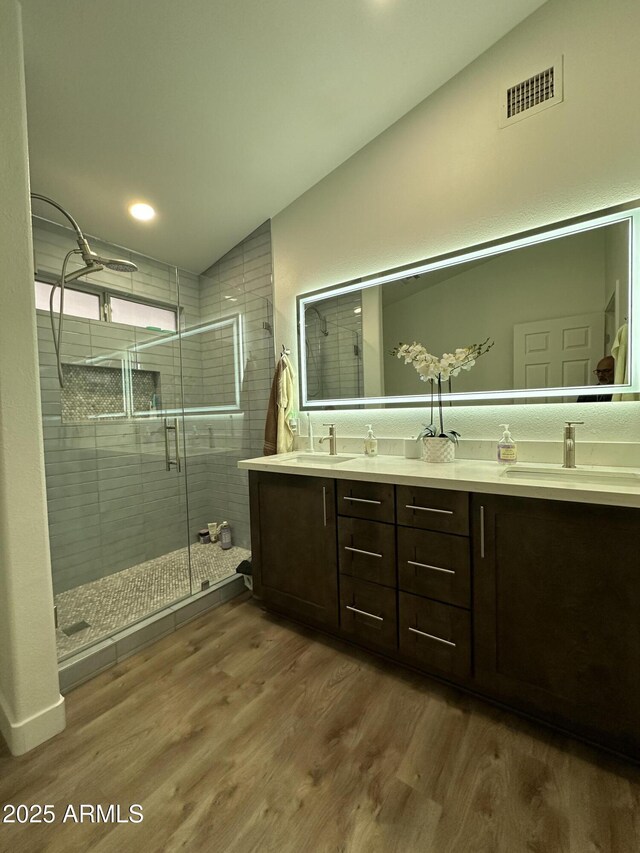 bathroom with vaulted ceiling, wood finished floors, a sink, and a shower stall