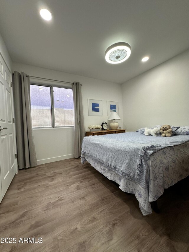 bedroom with baseboards, wood finished floors, and recessed lighting