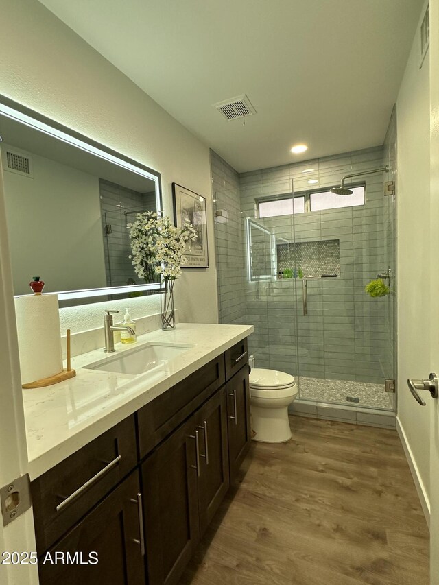 full bath featuring a stall shower, visible vents, toilet, and wood finished floors